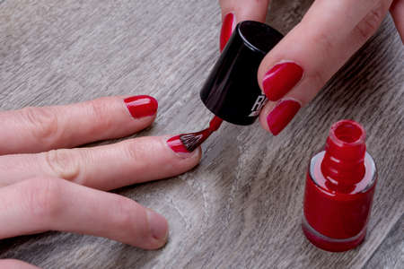 Close-up of female hands painting red nail varnishの写真素材
