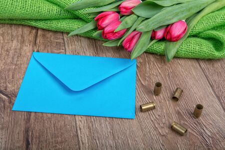 Blue envelope, tulips and bullets on a wooden backgroundの写真素材