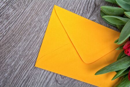 Envelope and red tulip on a wooden backgroundの写真素材