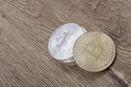 Silver bitcoins and one gold on a wooden table