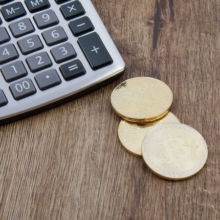 Bitcoins coins and calculator on a wooden tableの写真素材