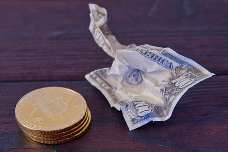 Dollar banknotes and Bitcoins on a dark wooden table