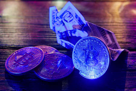 Dollar banknotes and Bitcoins on a dark wooden tableの写真素材