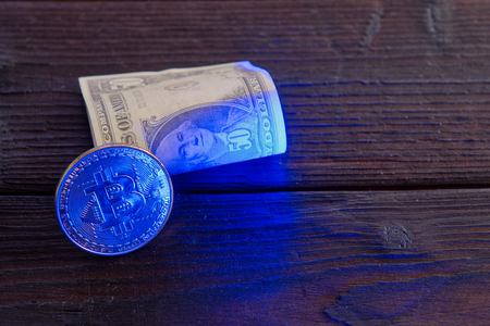 Dollar banknotes and Bitcoins on a dark wooden tableの写真素材