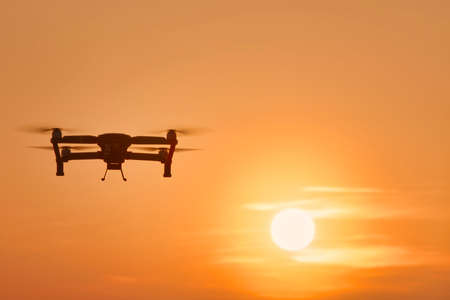 Drone quad copters with high resolution digital camera flying aerial over spectacular sunset orange...
