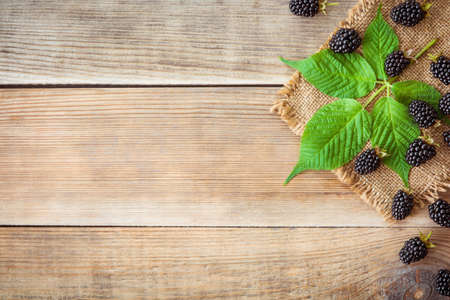 Fresh blackberries with leaves on wooden background in rustic style. Top view.の写真素材