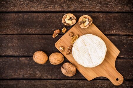 Camembert cheese with walnuts on wooden rustic background. Top view.の写真素材