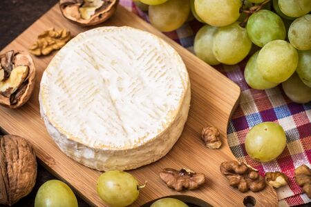 Camembert cheese with walnuts and green grapes on wooden rustic background. Selective focus.の写真素材