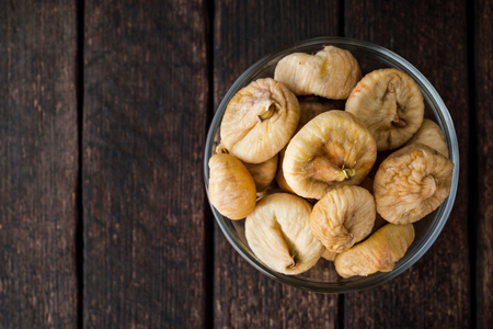 Dried figs in glass bowl on wooden background. Selective focus. Rustic style.の写真素材