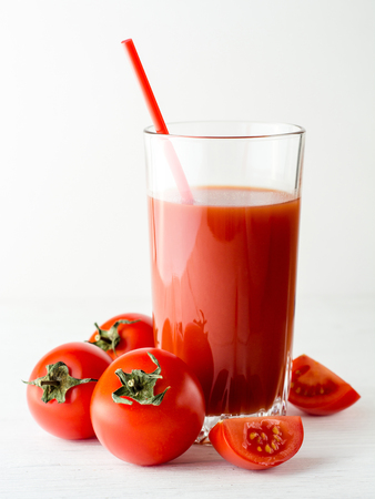 Tomato juice in glass and fresh tomatoes on white wooden table. Close-up.の写真素材
