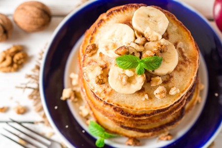 Pancakes with banana, honey, walnuts and mint on plate. Selective focus.の写真素材