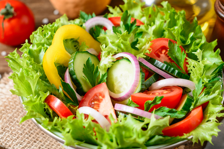 Fresh vegetable salad with greens on wooden table. Healthy vegetarian food. Selective focus.の写真素材