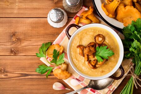 Mushroom cream soup with chanterelles and parsley on wooden background. Top view.の写真素材