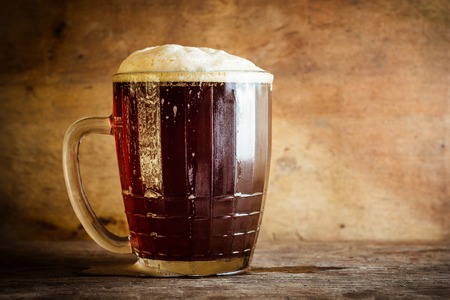 Beer in mug on rustic wooden background. Side view and copy space.