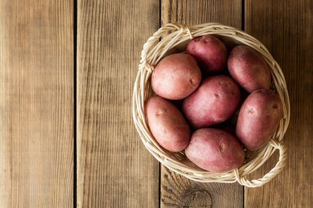 Raw potatoes in basket on wooden background. Top view with copy space.の写真素材