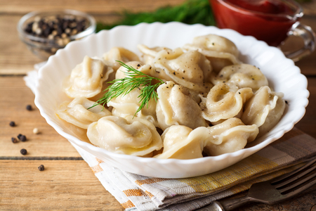 Russian meat dumplings pelmeni with dill on wooden rustic background. Selective focus.の写真素材