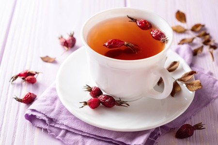 Cup of herbal tea from rose hips on purple wooden background. Selective focus.の写真素材