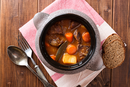Meat stew with vegetables in ceramic pot on wooden table. Top view.の写真素材