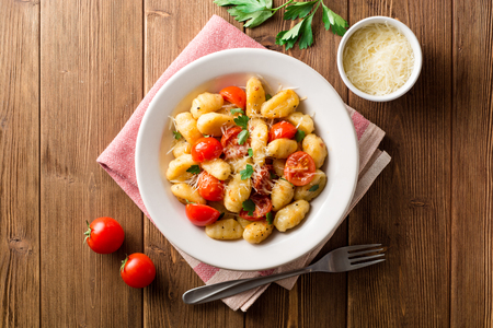 Homemade italian gnocchi with tomato, garlic, parsley and parmesan cheese on wooden table. Top view.の写真素材