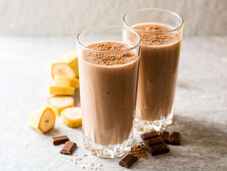 Chocolate banana smoothie in glass on gray stone background. Selective focus.の写真素材