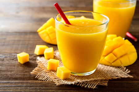 Mango smoothie in glass on dark wooden background. Selective focus.の写真素材