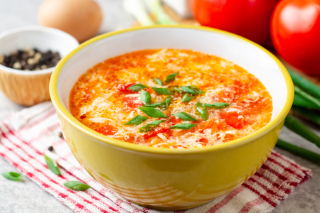Traditional chinese egg drop soup with tomato and green onion in bowl on gray stone background. Selective focus.の写真素材