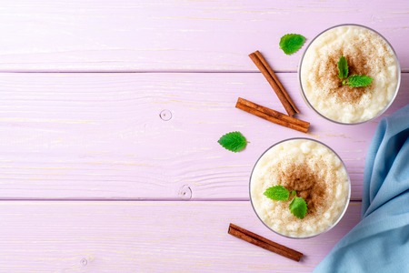 Rice pudding with cinnamon and mint on light purple wooden background. Top view. Copy space.の写真素材