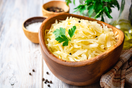 Homemade sauerkraut with black pepper and parsley in wooden bowl on rusticの写真素材