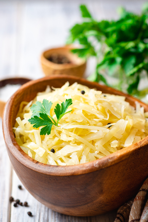 Homemade sauerkraut with black pepper and parsley in wooden bowl on rusticの写真素材