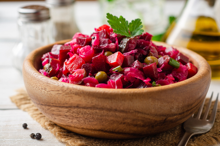 Traditional russian salad vinaigrette with boiled vegetables, pickled cucumbers and sauerkraut in bowl on white wooden table. Selective focus.の写真素材
