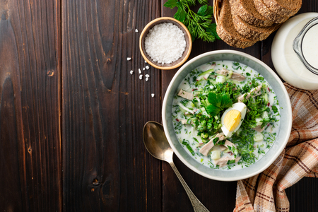 Traditional Russian summer cold soup okroshka with kefir in bowl on dark wooden background. Top view. Copy space.の写真素材