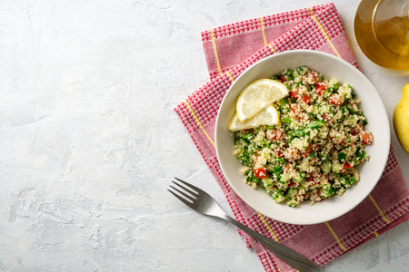 Traditional Arabic Salad Tabbouleh with couscous, vegetables and greens on concreteの写真素材