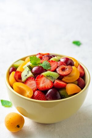 Healthy fresh fruit salad in bowl on gray concrete background. Selective focus.の写真素材