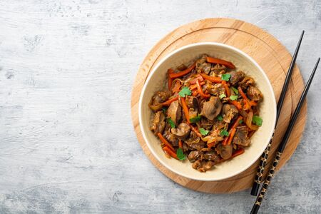 Fried chicken gizzards with carrot and onion in bowl on concreteの写真素材
