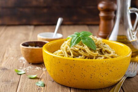 Spaghetti pasta with sauce pesto and parmesan cheese in ceramic bowl on wooden table. Selective focus.の写真素材
