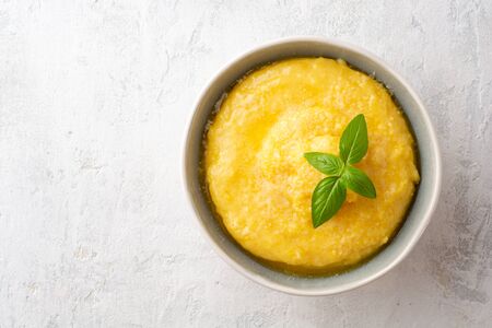Polenta with butter and parmesan cheese in bowl on concreteの写真素材