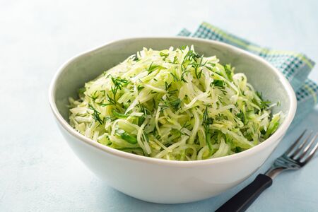Fresh cabbage and cucumber salad with dill in bowl on concrete background. Coleslaw. Selective focus.の写真素材