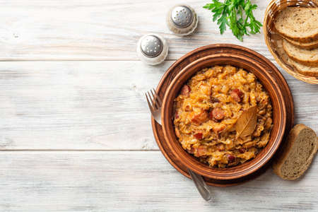 Traditional Polish dish Bigos in ceramic bowl on rustic wooden table. Top view, copy space.の写真素材