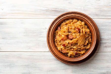 Traditional Polish dish Bigos in ceramic bowl on rustic wooden table. Top view, copy space.の写真素材