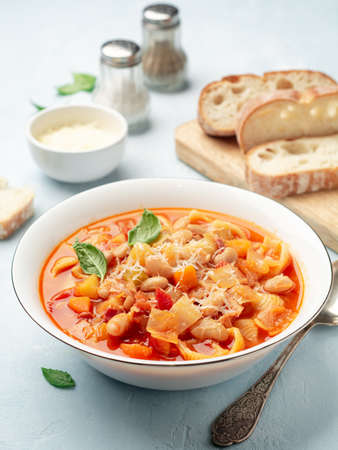 Italian minestrone soup with parmesan cheese and basil on blue concrete background. Selective focus.の写真素材