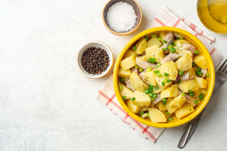 Potato salad with salted herring and onion in ceramic bowl on concrete background. Top view, copy space.の写真素材