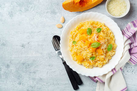 Pumpkin risotto with parmesan cheese and basil leaves on concrete background. Top view, copy space.の写真素材
