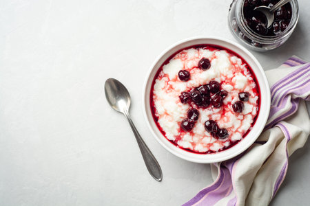 Rice pudding or porridge with cherry jam in bowl on concrete background. Top view, copy space.の写真素材