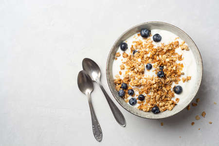 Yogurt with granola and blueberries in bowl on concrete background. Top view, copy space.の写真素材