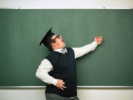 Male nerd playing air guitar in front of blackboardの写真素材