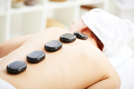 Woman having hot stones on her back in spa salonの写真素材