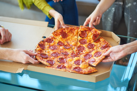 People eating pizza at home, unrecognizable personsの写真素材