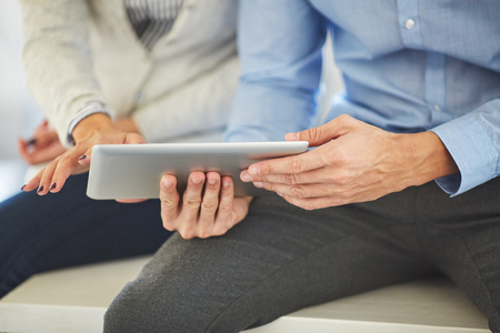 Two colleagues in office watching tablet, unrecognizable peopleの写真素材