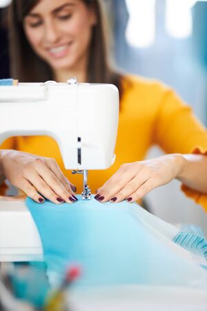 Close up of smiling caucasian seamstress sewing beautiful evening dress.の写真素材