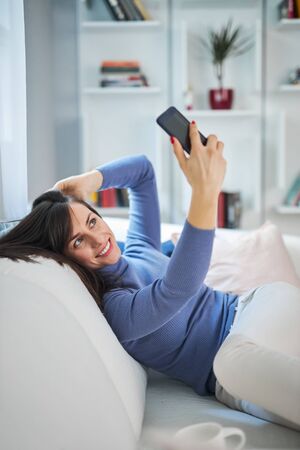 Young attractive smiling brunette taking selfie. She is gonna post  on social media.の写真素材